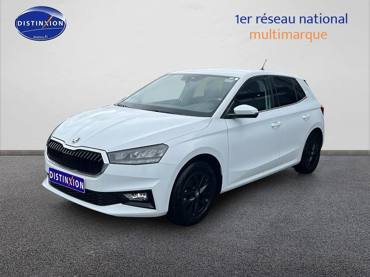 SKODA FABIA blanche vue 3/4 avant droit avec jantes noires et calandre chromée sur fond neutre.