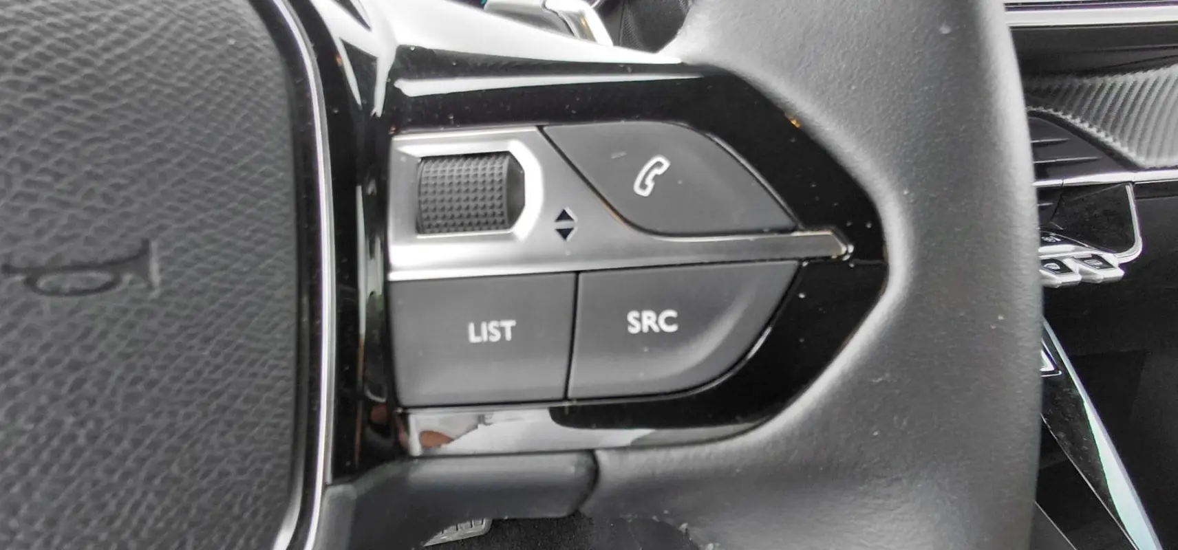 Gros plan sur les commandes gauche du volant noir du Peugeot 2008 Hybrid 145 e-DCS6 Style 2025.