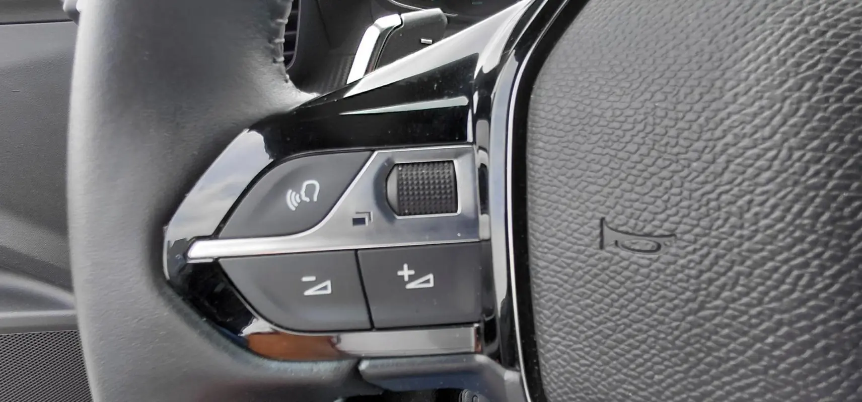 Détail du côté gauche du volant noir du Peugeot 2008 Hybrid 145 e-DCS6 Style 2025 montrant les commandes audio.