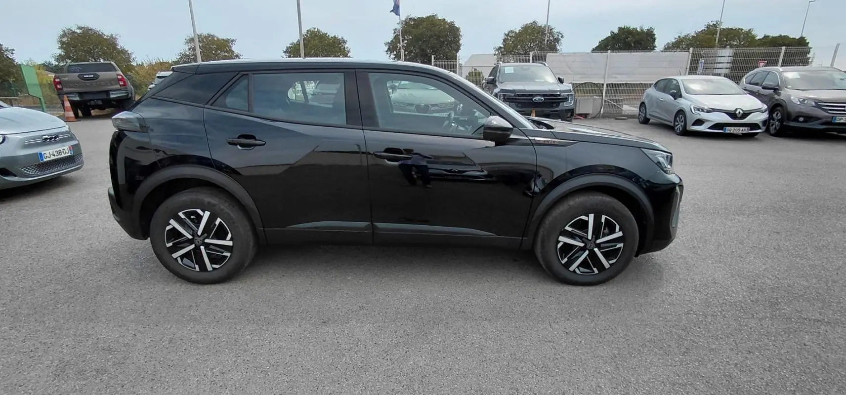 Peugeot 2008 Hybrid 145 e-DCS6 Style noir vu de profil côté gauche sur un parking extérieur.