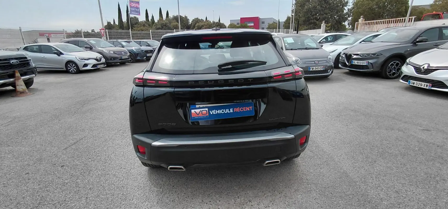 Vue arrière d’un Peugeot 2008 Hybrid 145 noir 2025, avec feux arrière LED et double sortie d’échappement visible.