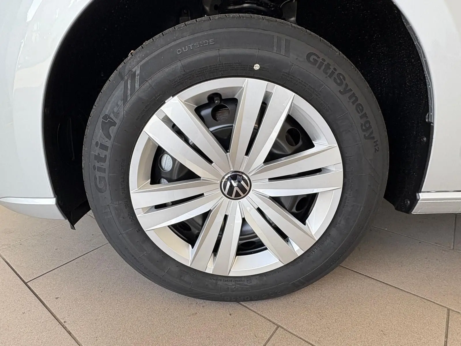 Gros plan sur la roue avant gauche gris argent du Volkswagen Caddy 2025 avec jante en alliage et logo VW central.