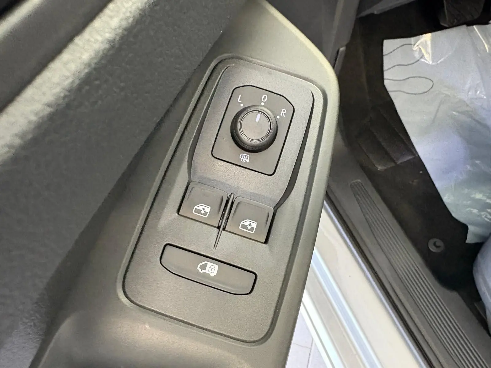 Gros plan sur les commandes des rétroviseurs et vitres côté conducteur du Volkswagen Caddy gris argent 2025.