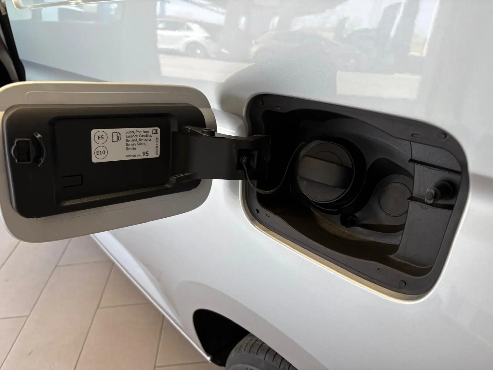 Bouchon de réservoir essence ouvert sur le côté gauche d'un Volkswagen Caddy gris argent 2025, version Business.