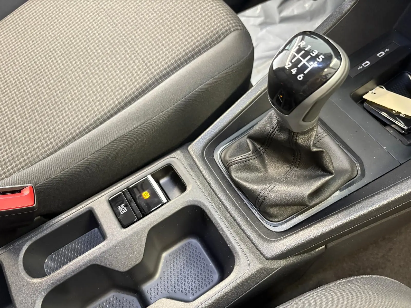 Gros plan sur la console centrale du Volkswagen Caddy 2025 gris argent, mettant en valeur le levier de vitesses manuel et le frein à main électronique.