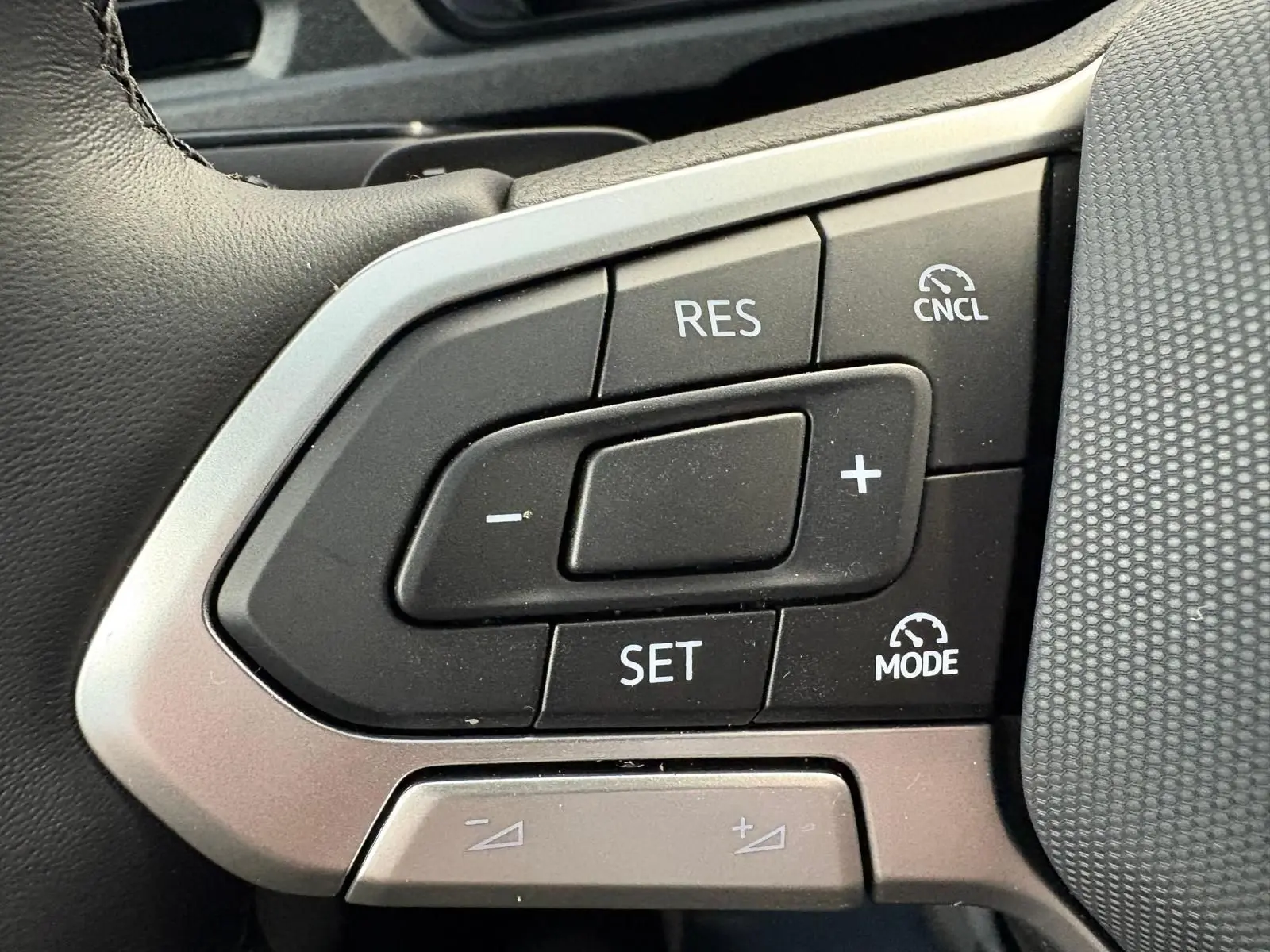 Gros plan sur les commandes de régulateur de vitesse au volant d'un Volkswagen Caddy gris argent 2025.