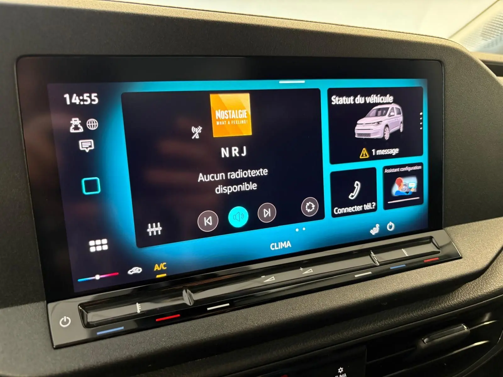 Écran tactile central du Volkswagen Caddy 2025 gris argent, affichant radio NRJ et statut véhicule avec message d'alerte.