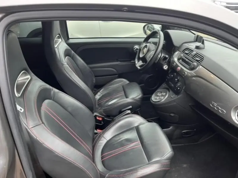 Vue intérieure côté gauche de l'Abarth 500 2013 avec sièges sport cuir noir et surpiqûres rouges, tableau de bord gris métallisé.