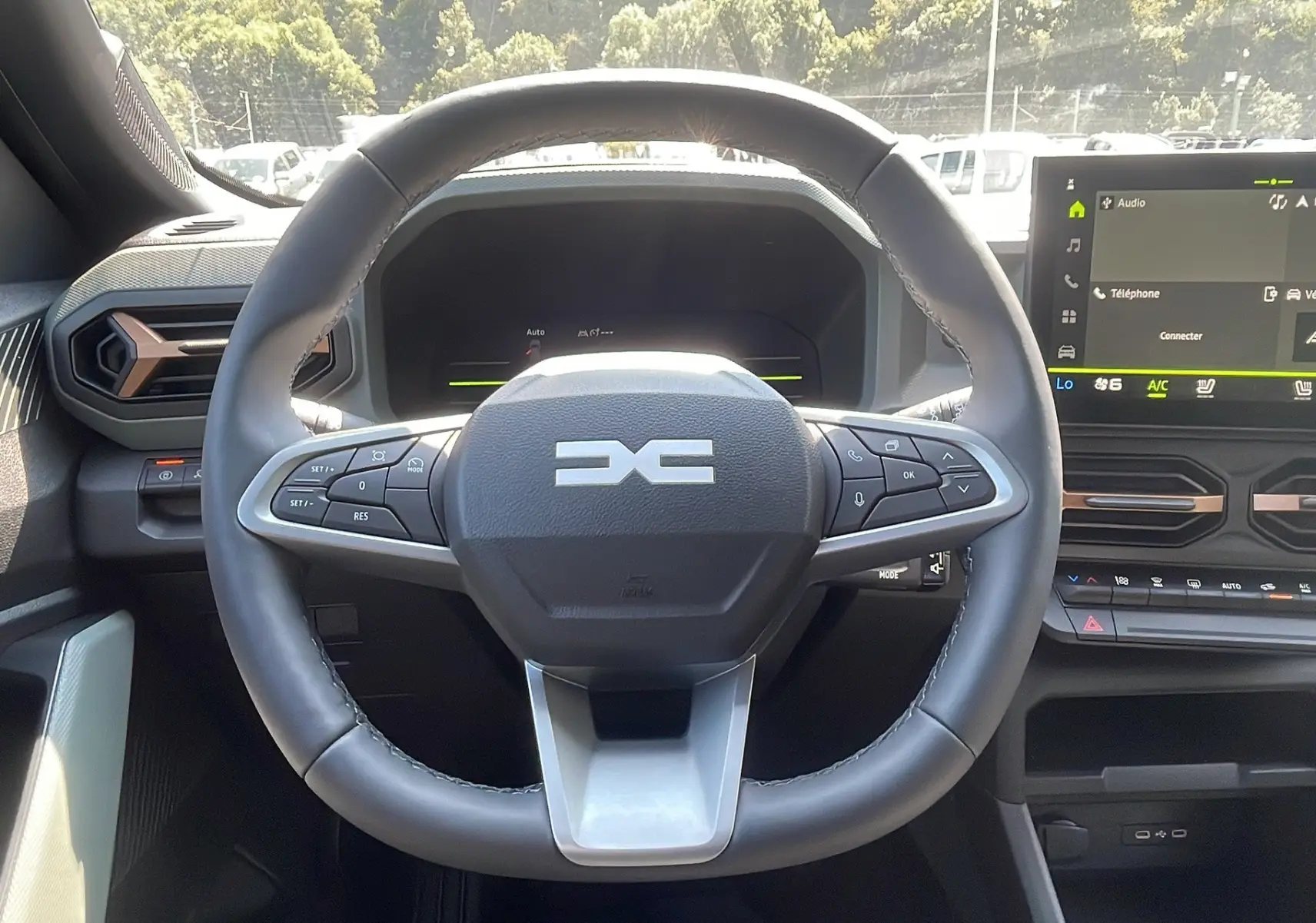 Vue rapprochée du volant multifonction du Dacia Duster 2025, avec tableau de bord numérique et écran tactile.