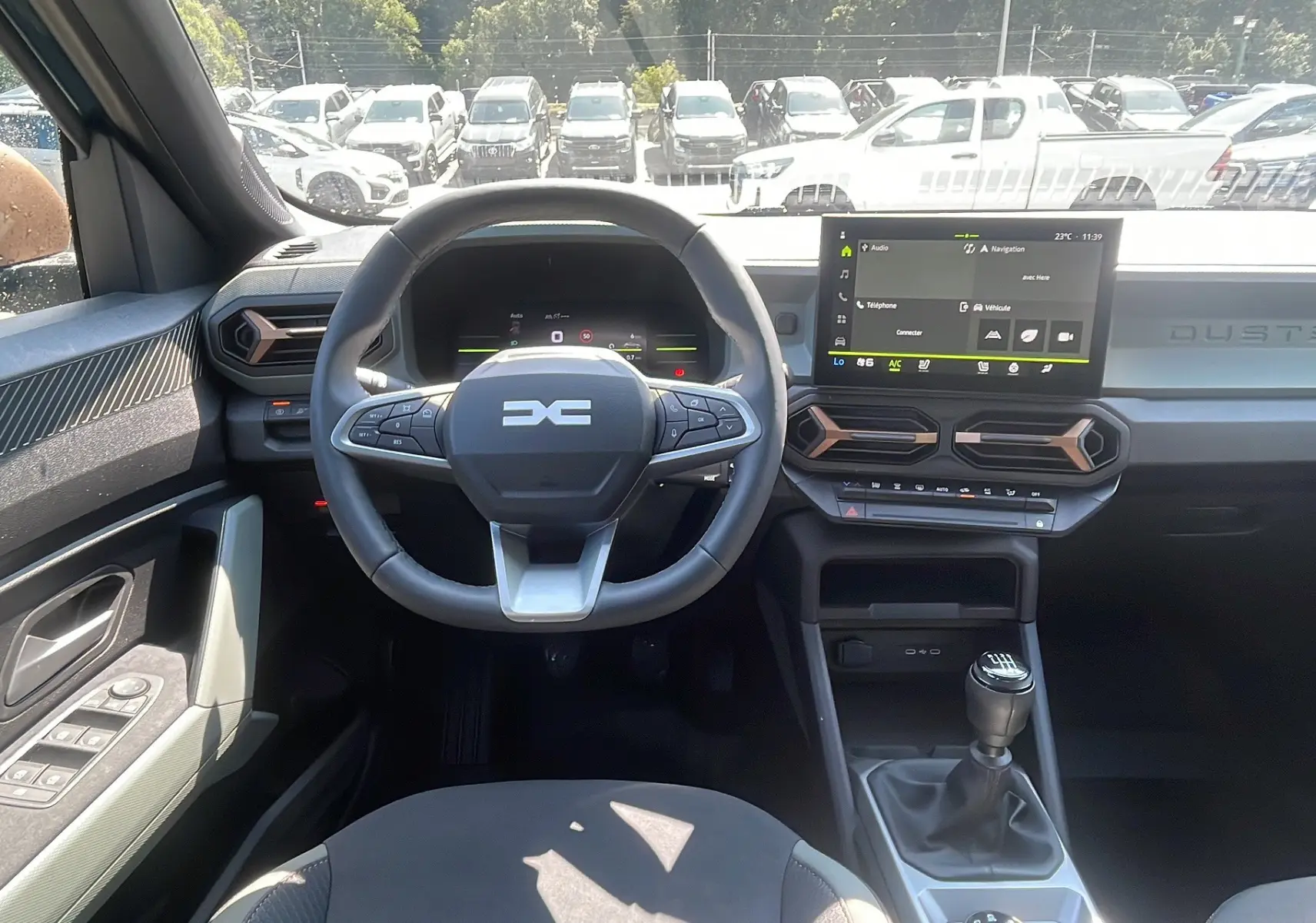 Vue intérieure du tableau de bord du Dacia Duster 2025 vert cèdre, avec volant multifonction et écran tactile central.