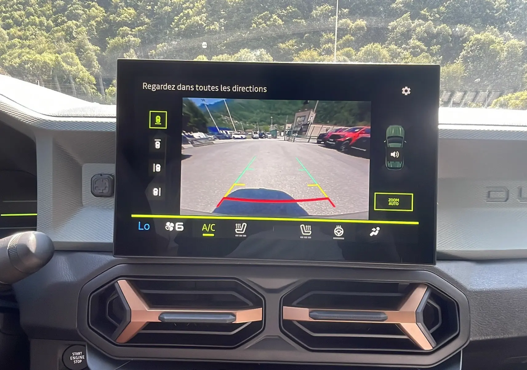 Vue intérieure du tableau de bord du Dacia Duster 2025 avec écran multimédia affichant la caméra de recul en marche.