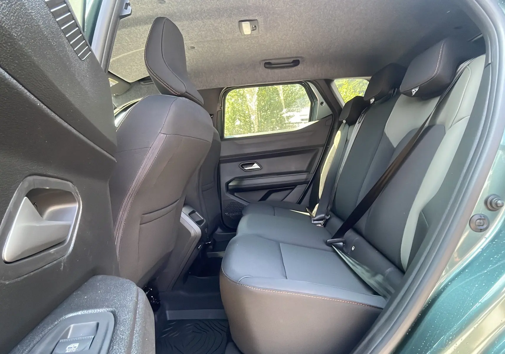Vue intérieure arrière droit du Dacia Duster 2025 vert cèdre, montrant les sièges arrière en tissu gris avec ceinture de sécurité.
