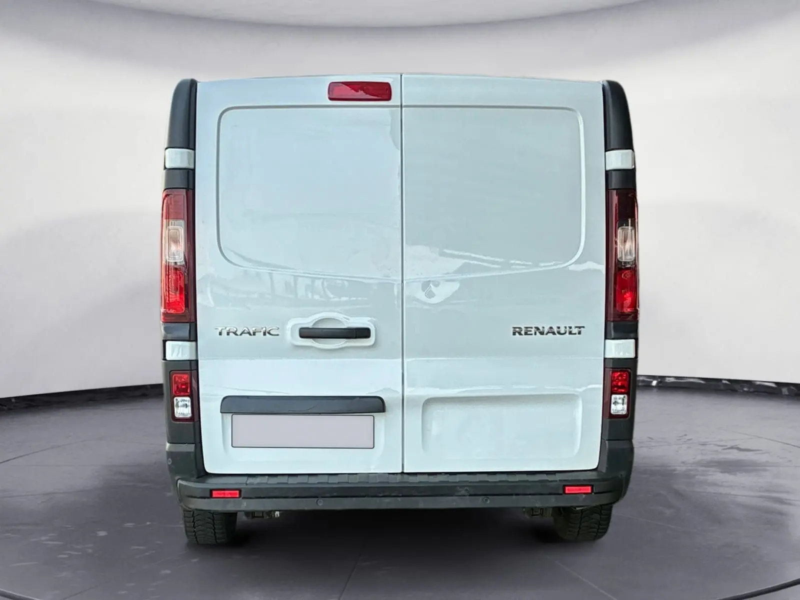 Vue arrière d'un fourgon blanc Renault Trafic L2H1 3T avec portes battantes et feux verticaux rouges.