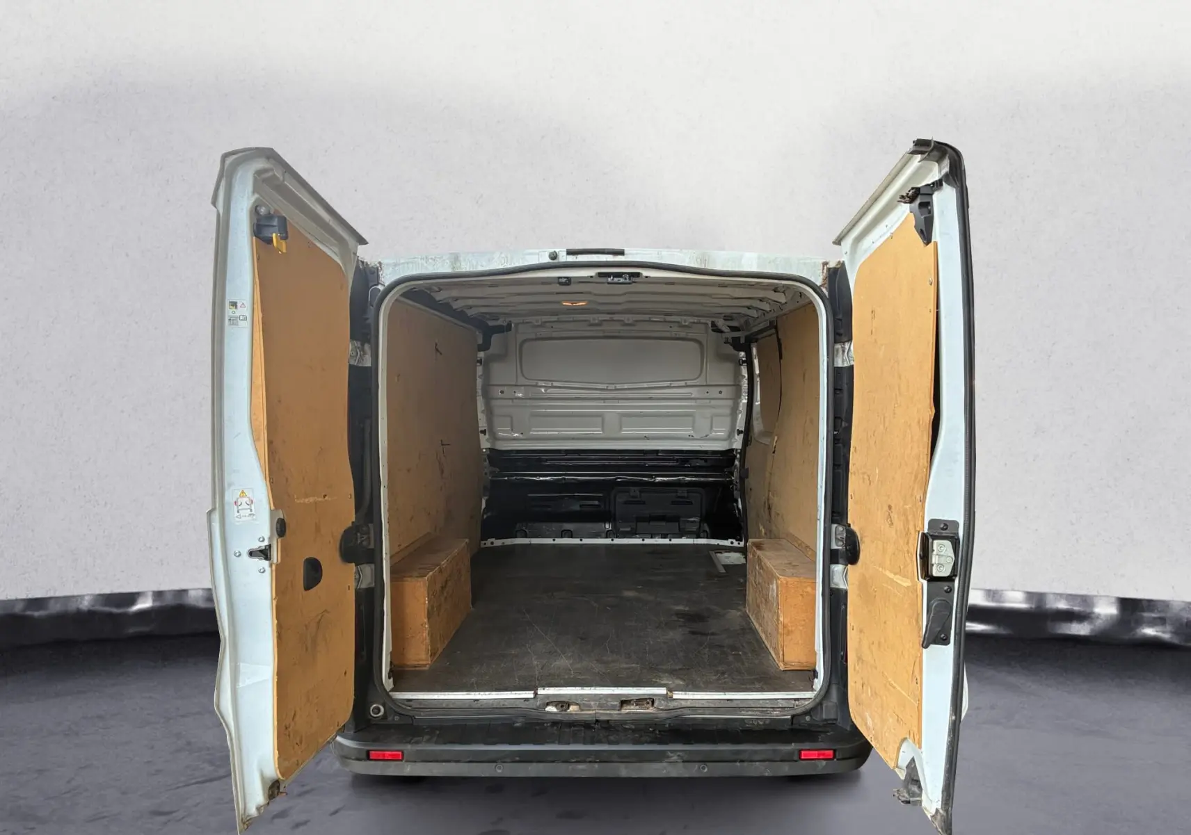 Vue arrière du Renault Trafic Fourgon blanc 2022 avec portes ouvertes montrant l'intérieur vide et panneaux en bois.