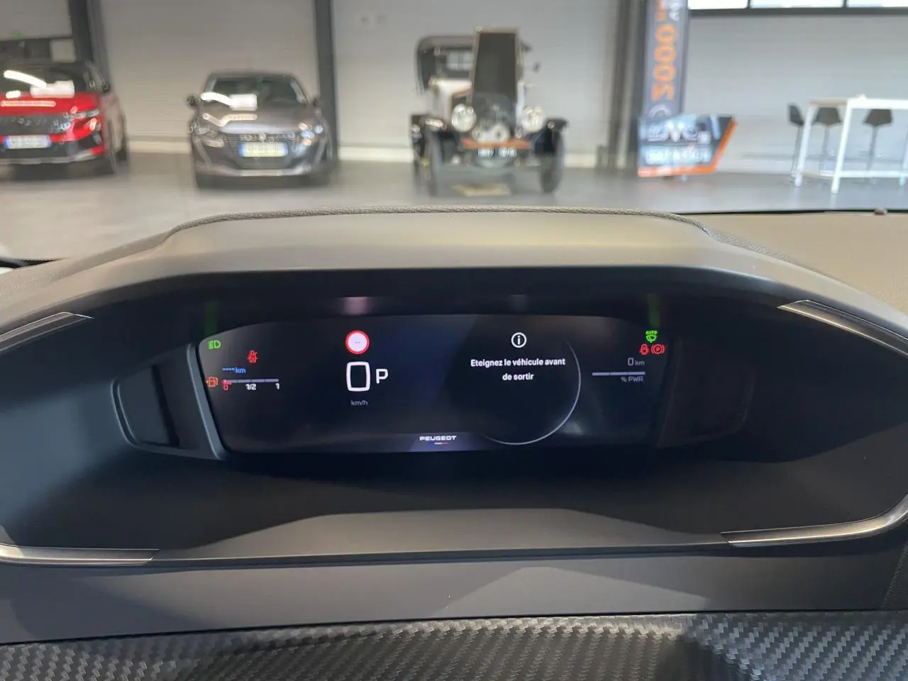 Vue rapprochée du tableau de bord numérique du Peugeot 208 noir hybride, affichant les informations de conduite et alertes.