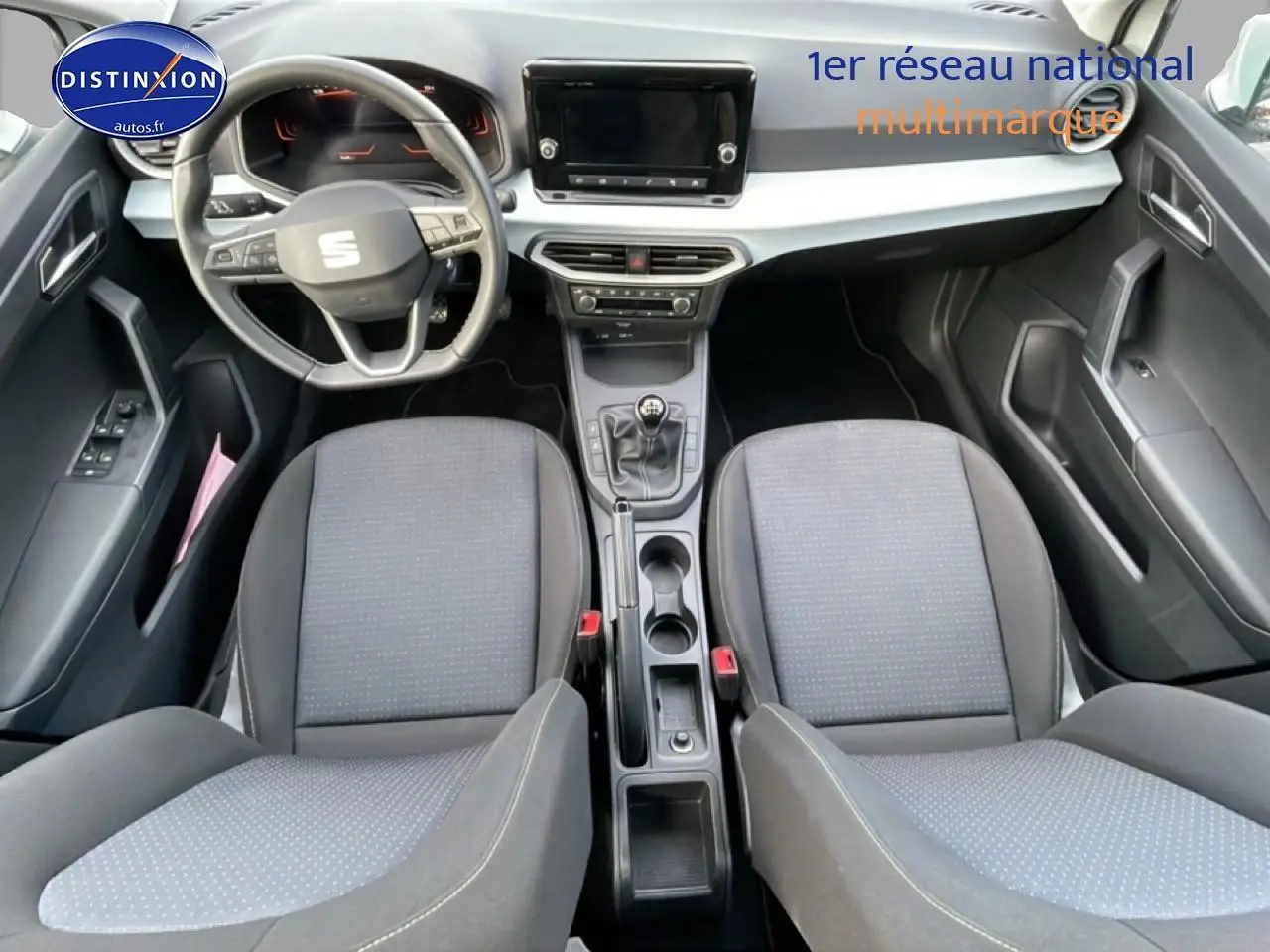 Vue intérieure de face du poste de conduite de la SEAT Ibiza 1.0 TSI 95 Copa avec sièges tissu gris et volant cuir multifonction.