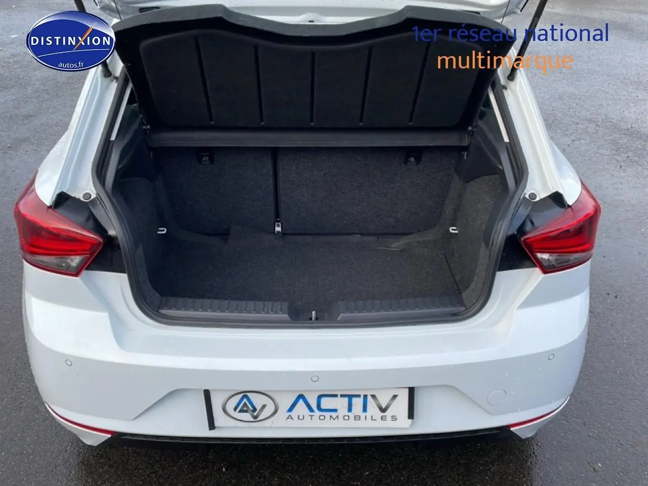 Vue arrière d’une SEAT Ibiza blanc Nevada 2025 avec coffre ouvert et feux arrière rouges visibles.