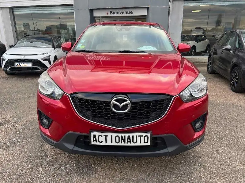 Vue avant d'un Mazda CX-5 2013 rouge Soul Red Métallisé avec calandre noire et phares allumés.
