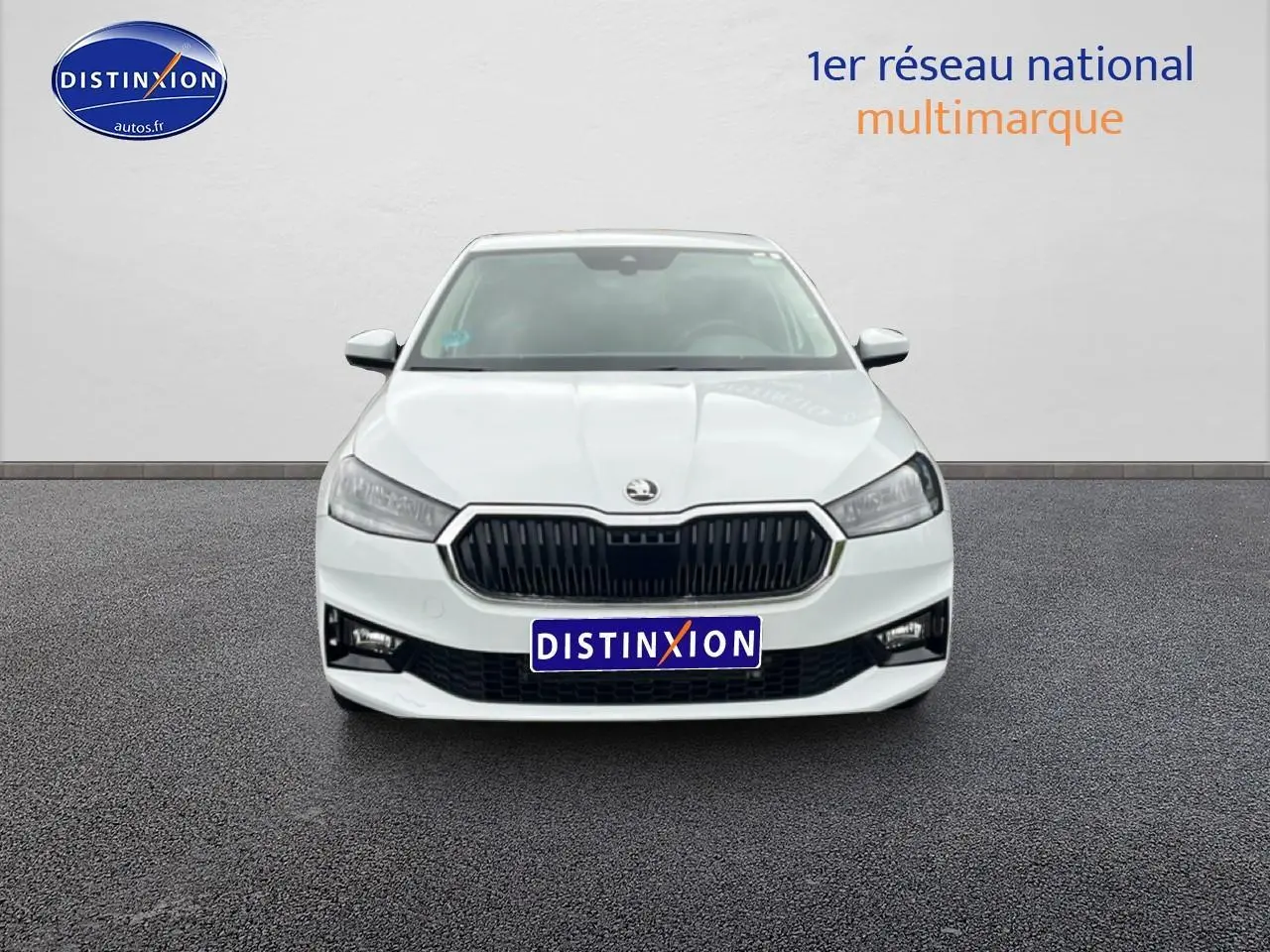 Vue de face d'une Skoda Fabia blanche 2025 avec calandre noire et phares LED, sur fond neutre intérieur showroom.