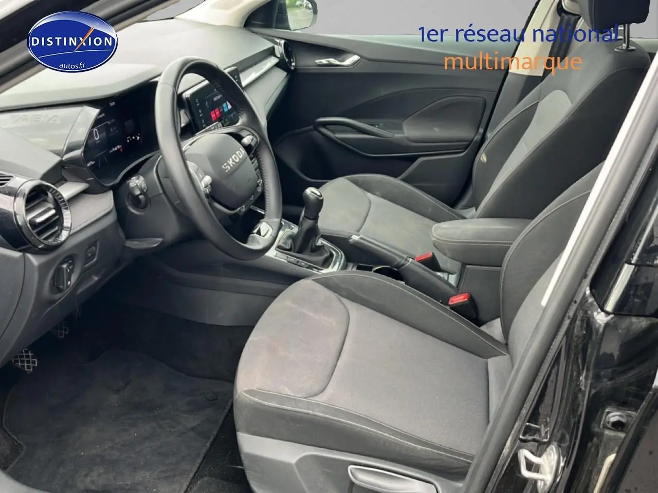 Intérieur avant droit d’une Skoda Fabia noire 2025, montrant sièges tissu gris et tableau de bord moderne.