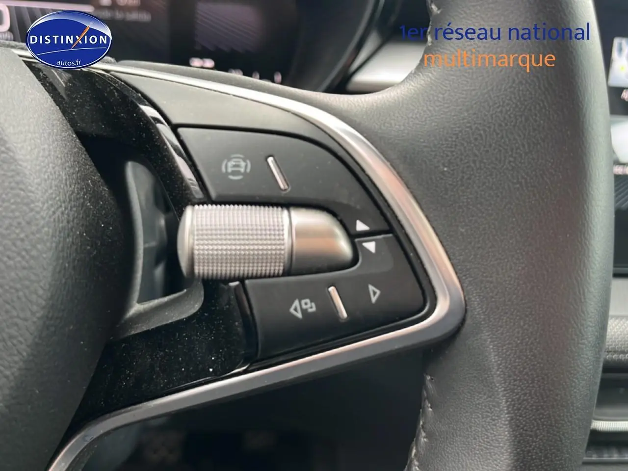 Gros plan sur les commandes multifonctions en métal et plastique noir du volant cuir côté gauche d’une Skoda Fabia noire.