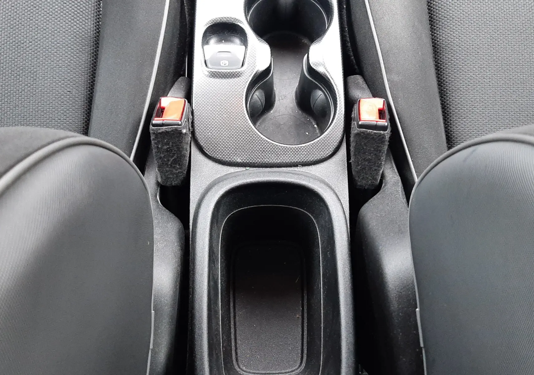 Vue plongeante sur la console centrale noire du Fiat 500X rouge, avec porte-gobelets et leviers de frein à main visibles.