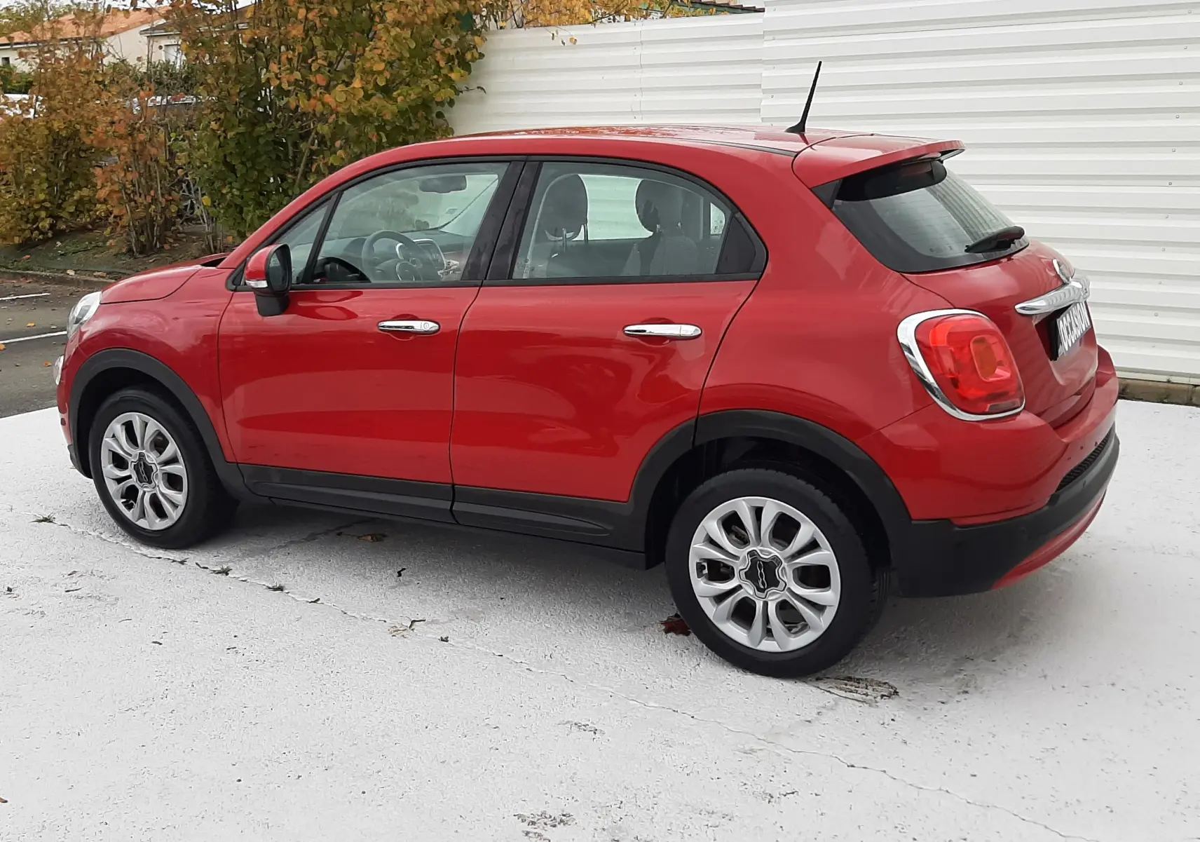 Vue de profil côté droit d'un FIAT 500X rouge 2016 avec jantes alliage et poignées chromées.