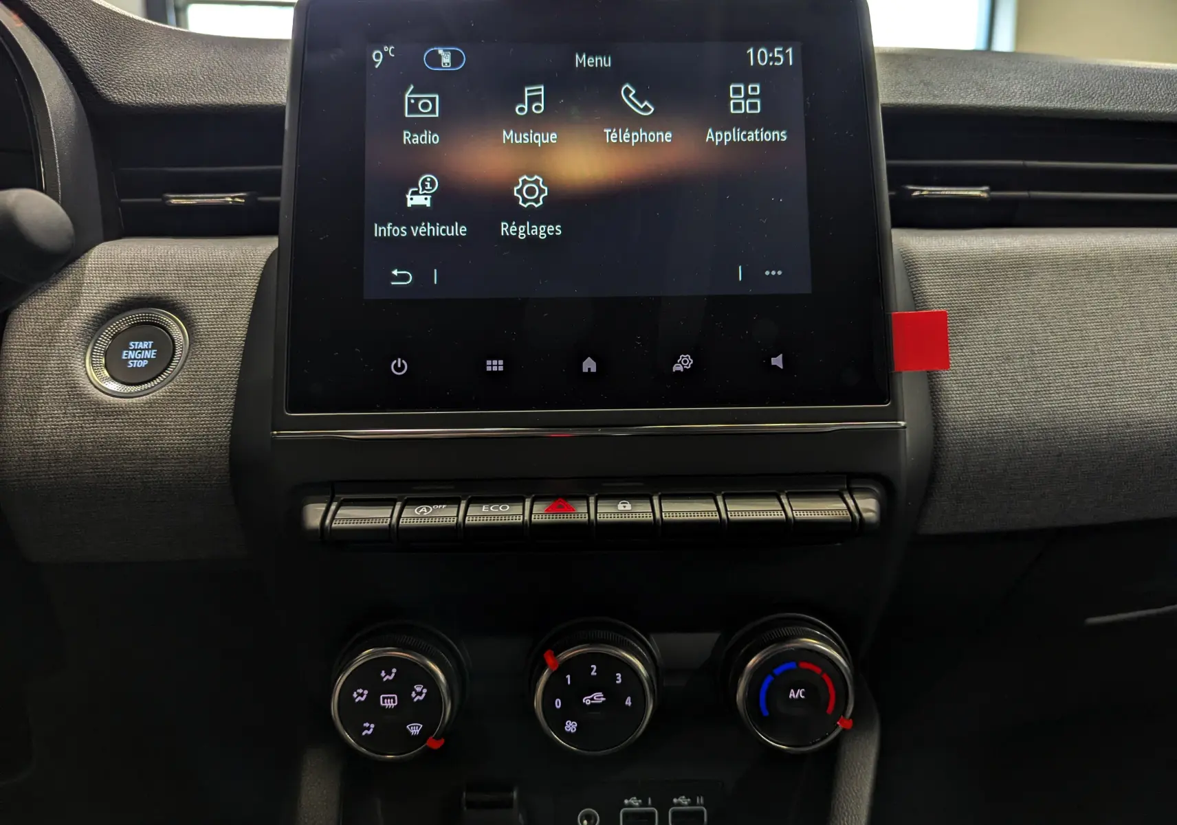 Vue rapprochée de la console centrale de la Renault Clio V 2025, écran tactile et commandes de climatisation visibles.