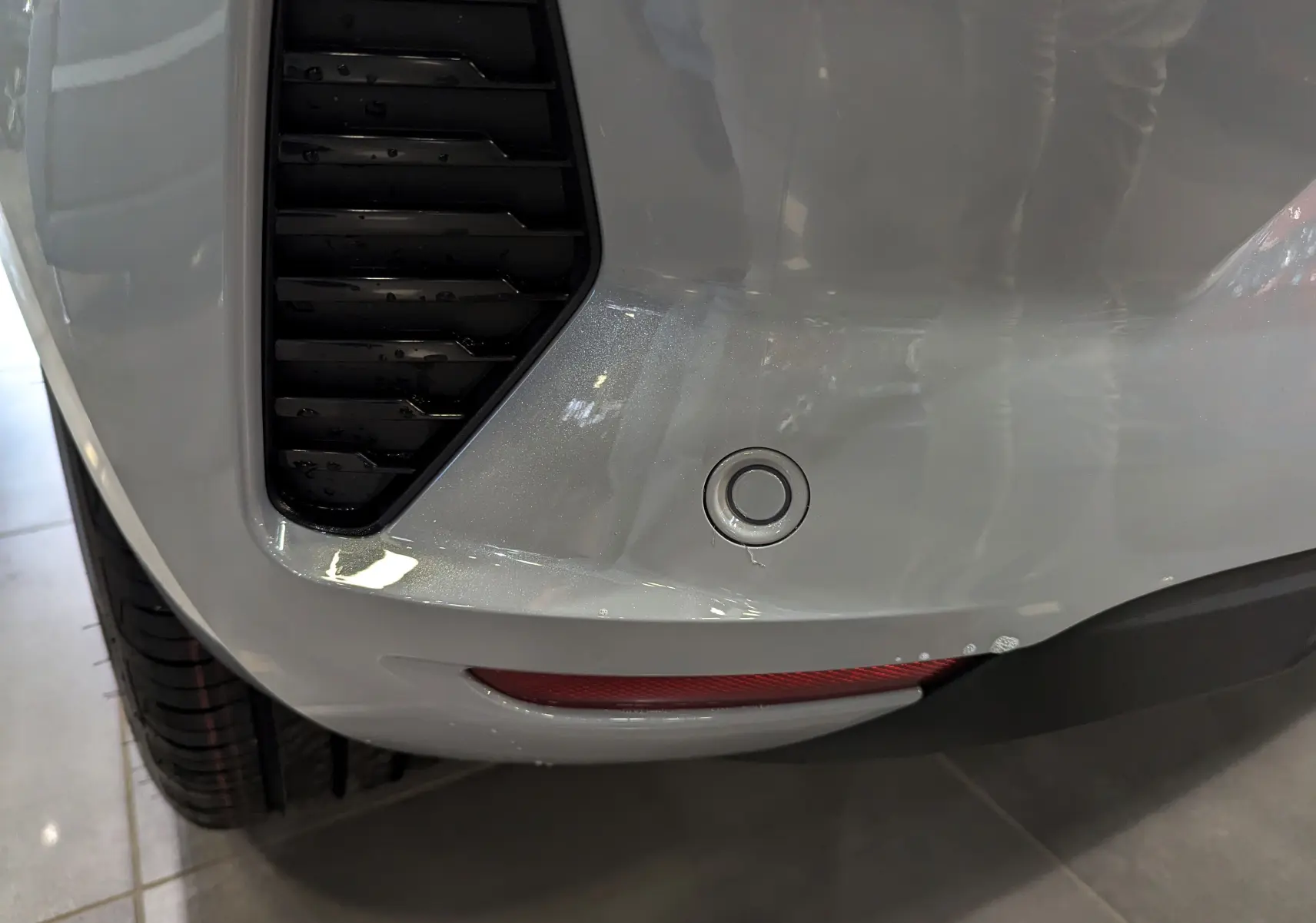 Gros plan sur le pare-chocs arrière gris Rafale d'une Renault Clio V, avec capteur de recul et feu réfléchissant rouge.