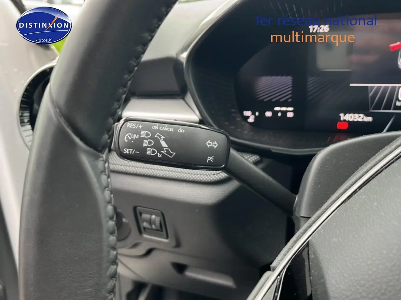 Gros plan sur le commodo gauche du volant cuir d'une Skoda Fabia blanche, affichage numérique en arrière-plan.