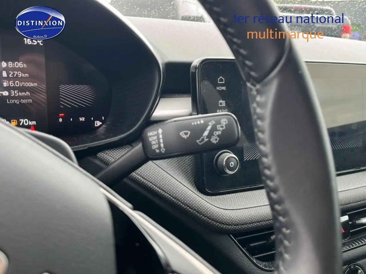 Vue rapprochée du tableau de bord et volant cuir noir de la Skoda Fabia blanche, avec écran tactile et commandes au volant visibles.