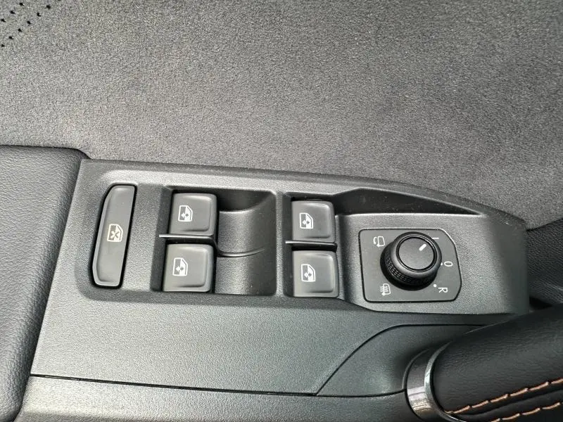 Gros plan sur les commandes de lève-vitres et réglage des rétroviseurs côté conducteur d'une CUPRA Formentor noir Minuit.