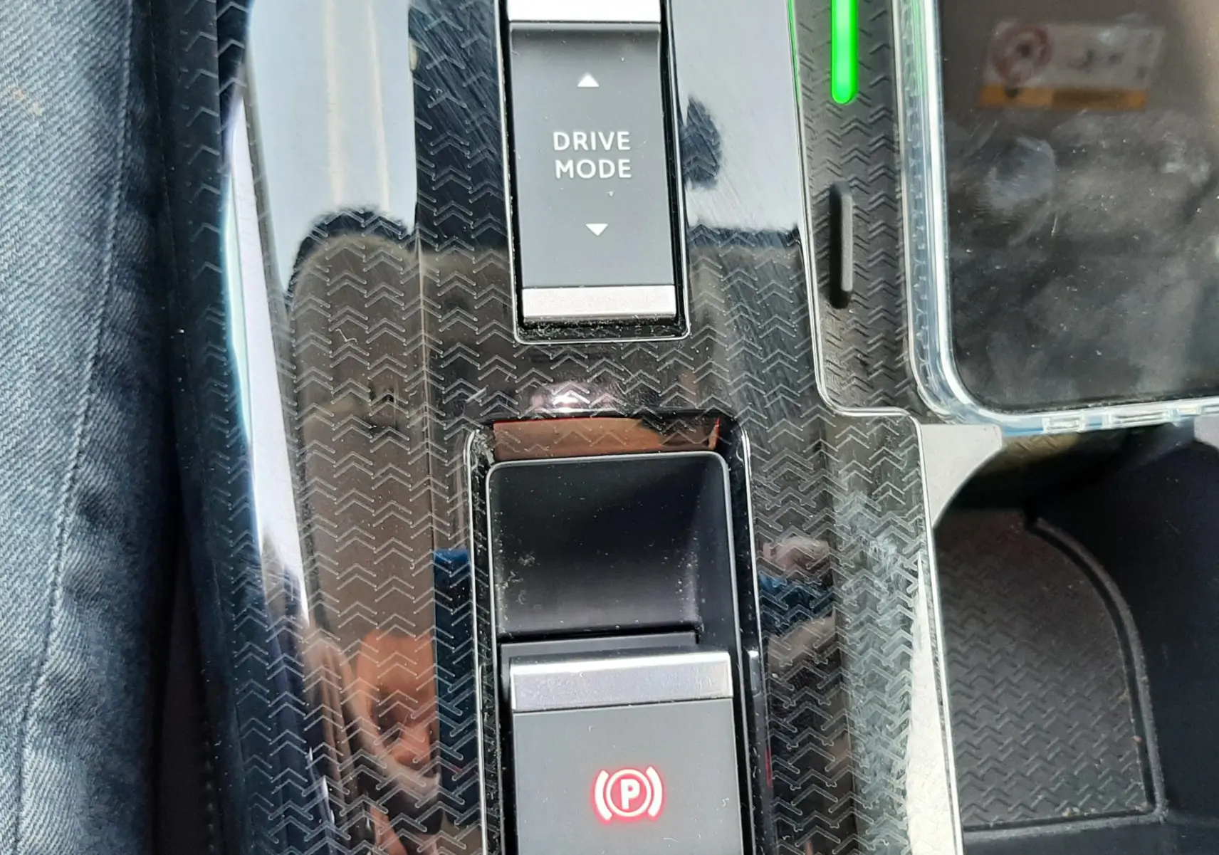 Gros plan sur la console centrale noire brillante du Citroën C5 Aircross hybride 2026 avec boutons Drive Mode et frein à main électronique.