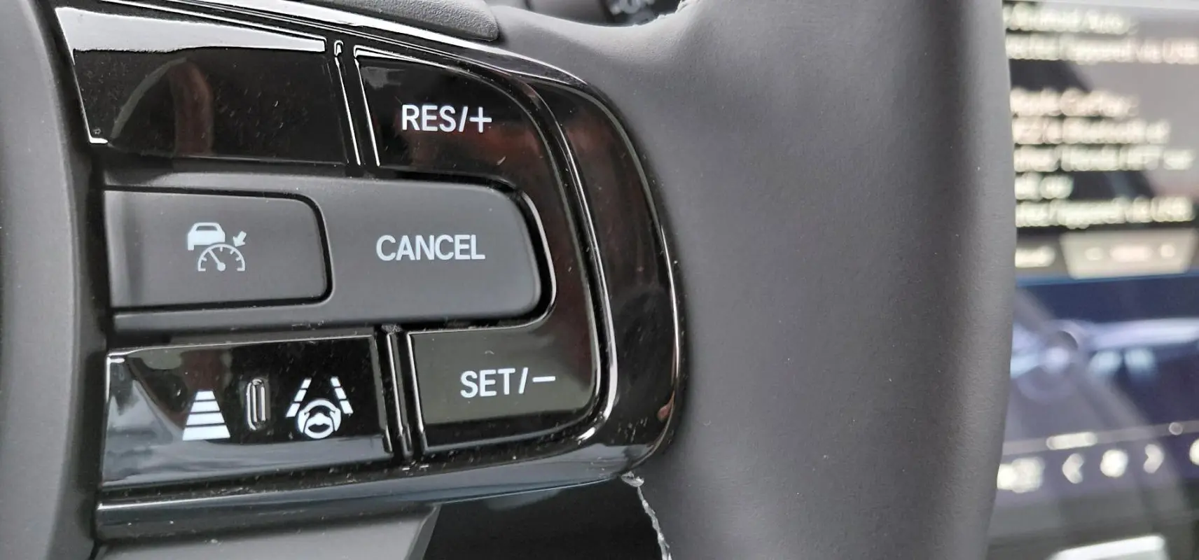 Gros plan sur les commandes de régulateur adaptatif au volant du Honda e:Ny1 Advance 2025, finition noire brillante.