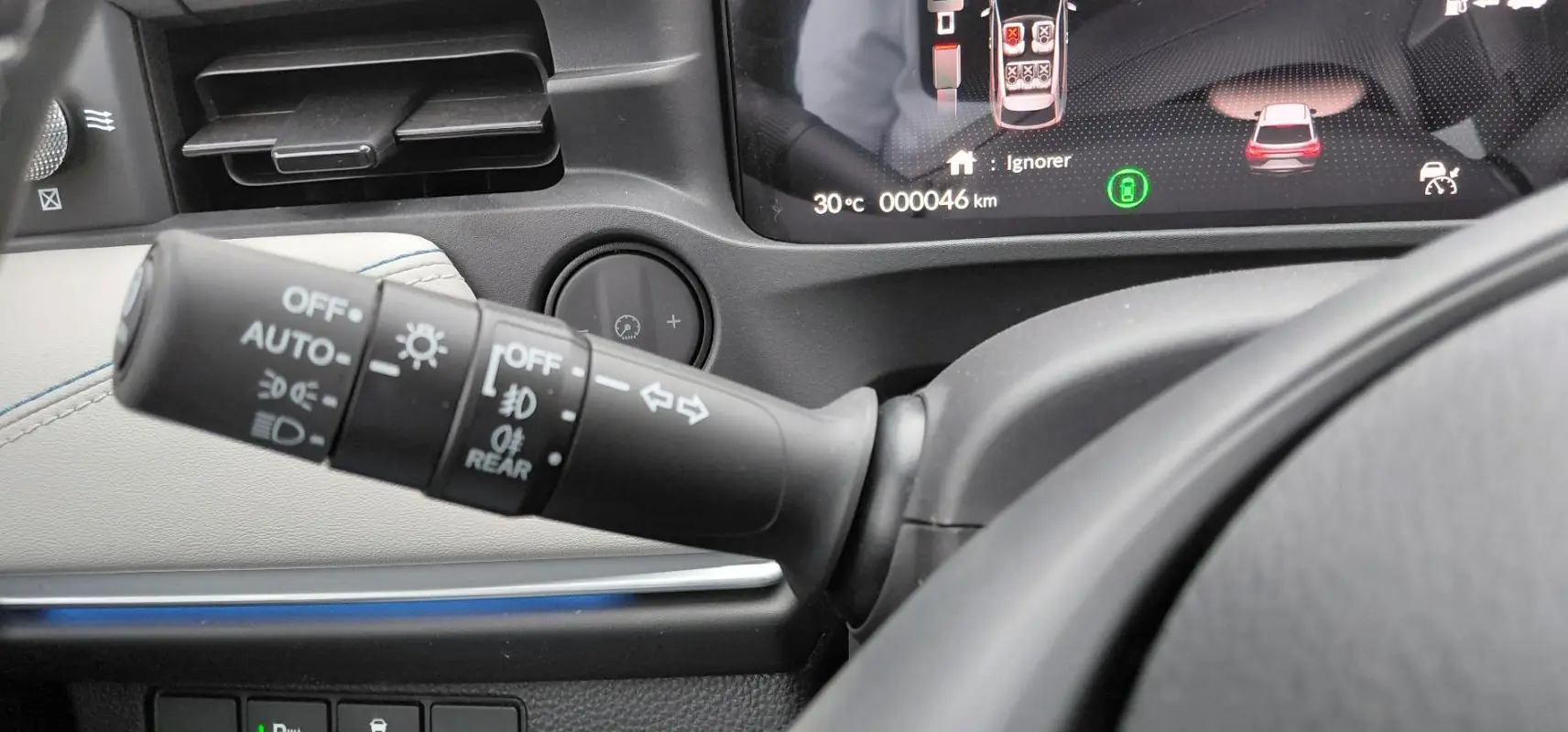 Gros plan sur la commande des feux et clignotants du Honda e:Ny1 204 ch Advance, avec tableau de bord numérique visible.