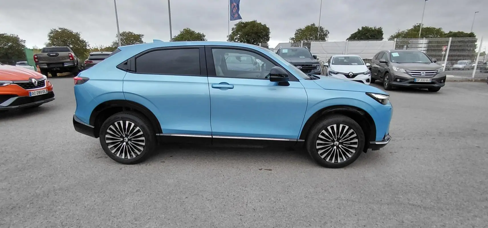 Vue de profil côté gauche d'un Honda e:Ny1 204 ch Advance 2025 bleu électrique avec jantes distinctives.