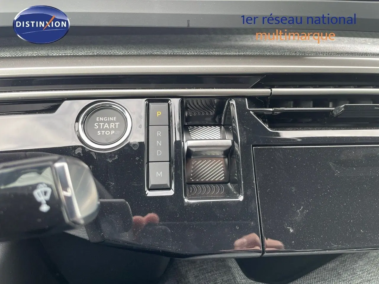 Gros plan sur la console centrale noire brillante du Peugeot 3008 Hybrid 2025 avec bouton start/stop et commandes de boîte auto.