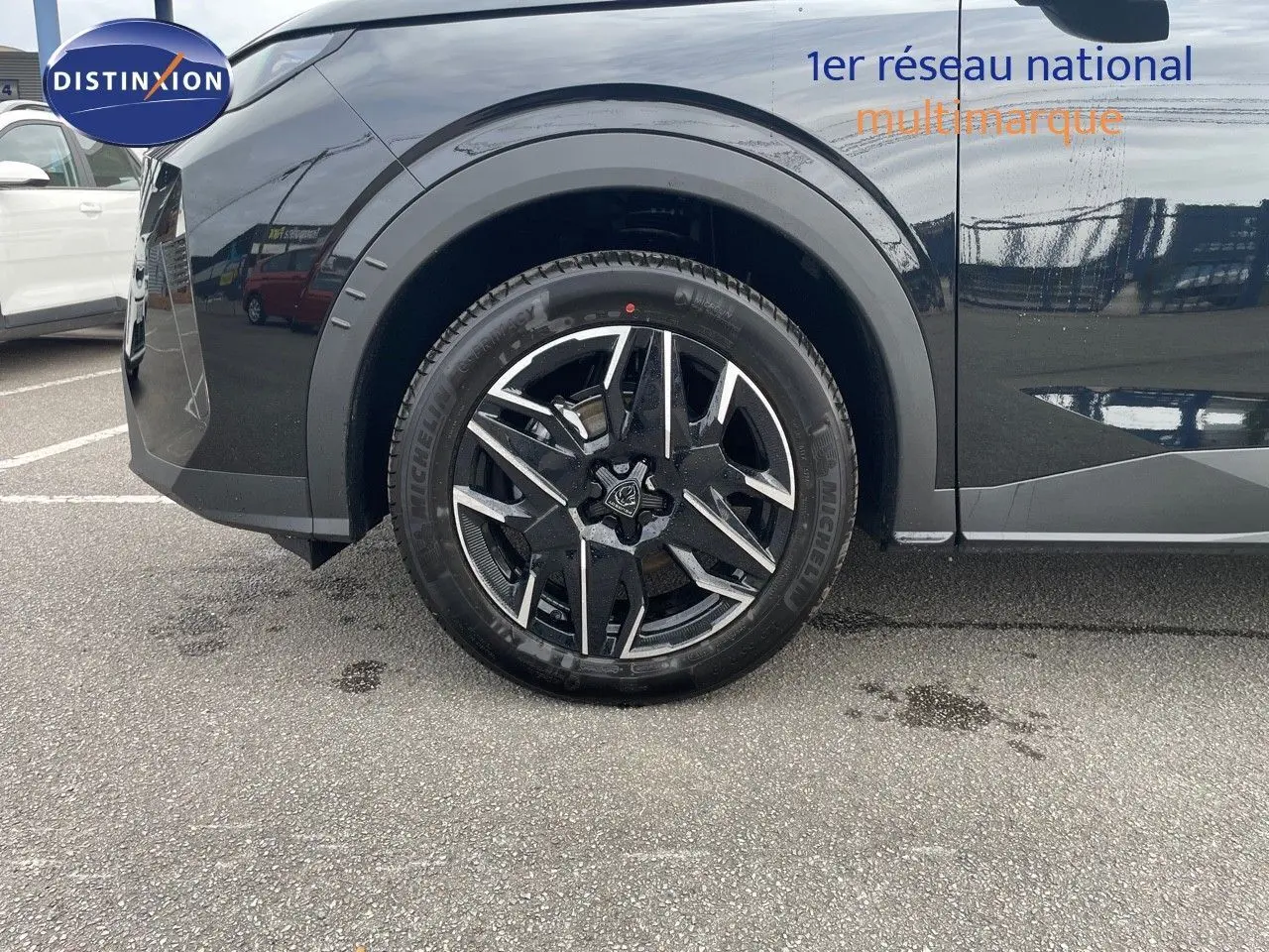 Gros plan sur la roue avant gauche du Peugeot 3008 noir perle métal, mettant en valeur la jante alliage bicolore.