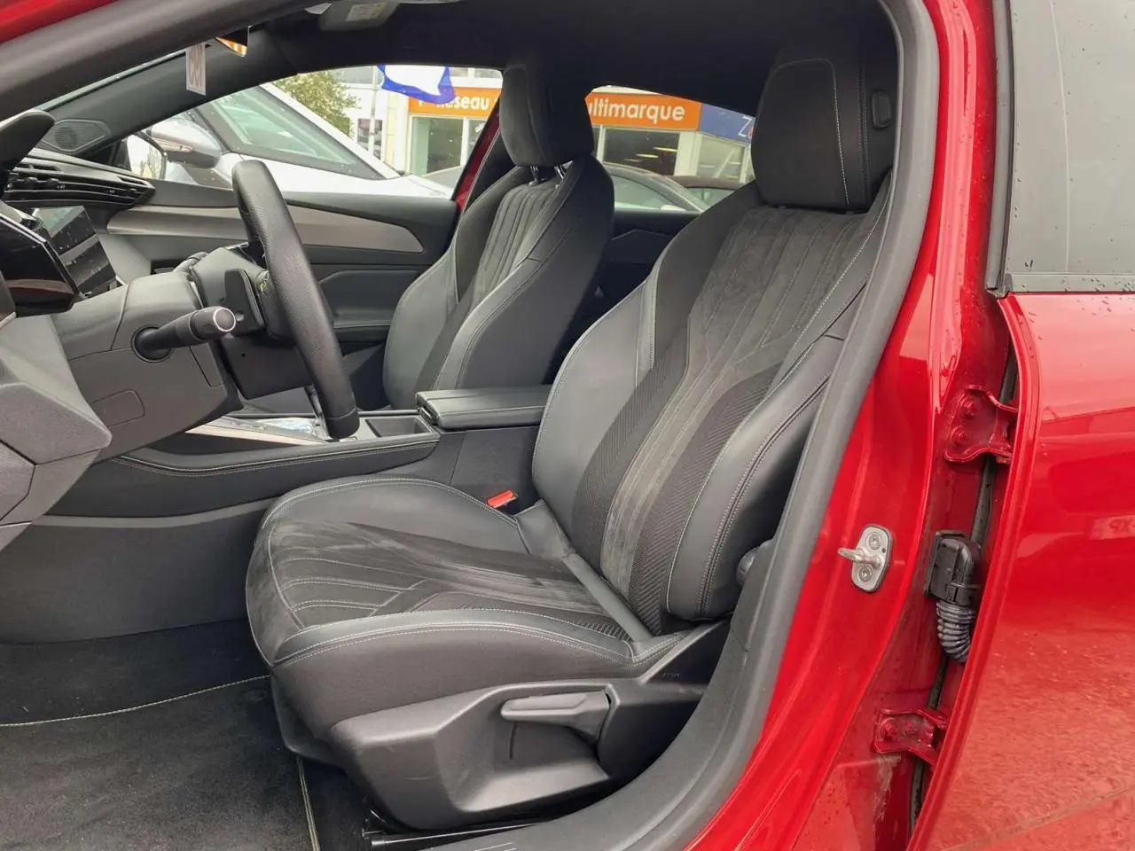 Intérieur côté conducteur de la Peugeot 308 rouge Elixir 2022, sièges sport en cuir et alcantara avec surpiqûres grises.
