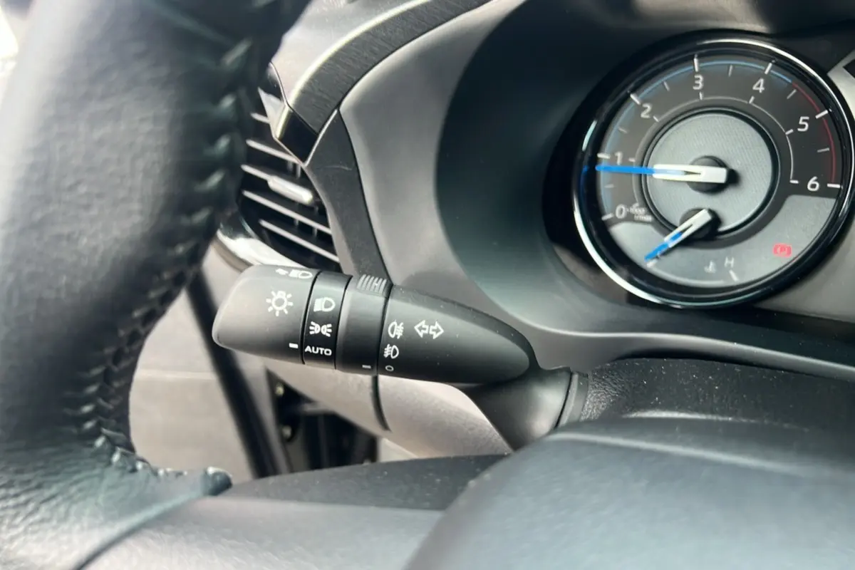 Gros plan sur la manette des phares et clignotants du Toyota Hilux 2025, intérieur noir avec compte-tours visible.