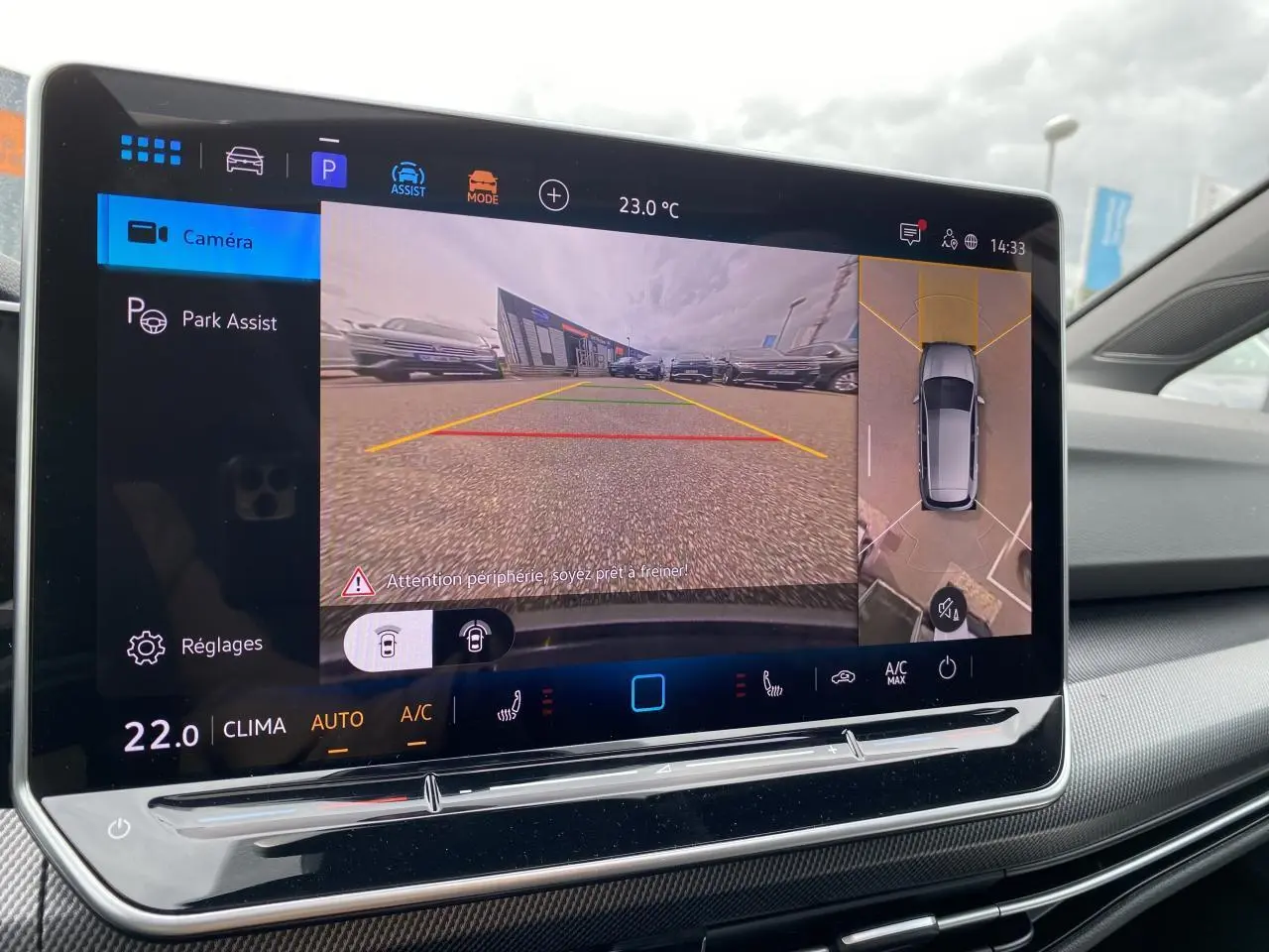 Écran tactile intérieur montrant la caméra 360° et l'aide au stationnement de la Volkswagen Golf 1.5 eTSI blanc nacré.