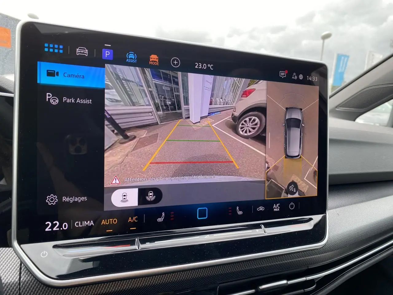 Écran tactile intérieur affichant la caméra 360° et l'assistance au stationnement de la Volkswagen Golf VIII R-Line blanc Oryx.