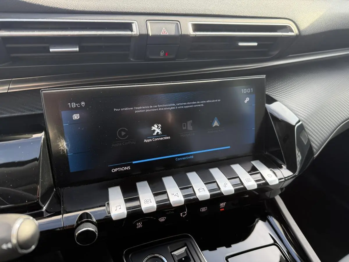 Vue rapprochée de la console centrale noire brillante avec écran tactile 10 pouces et commandes piano chromées du Peugeot 508 bleu.
