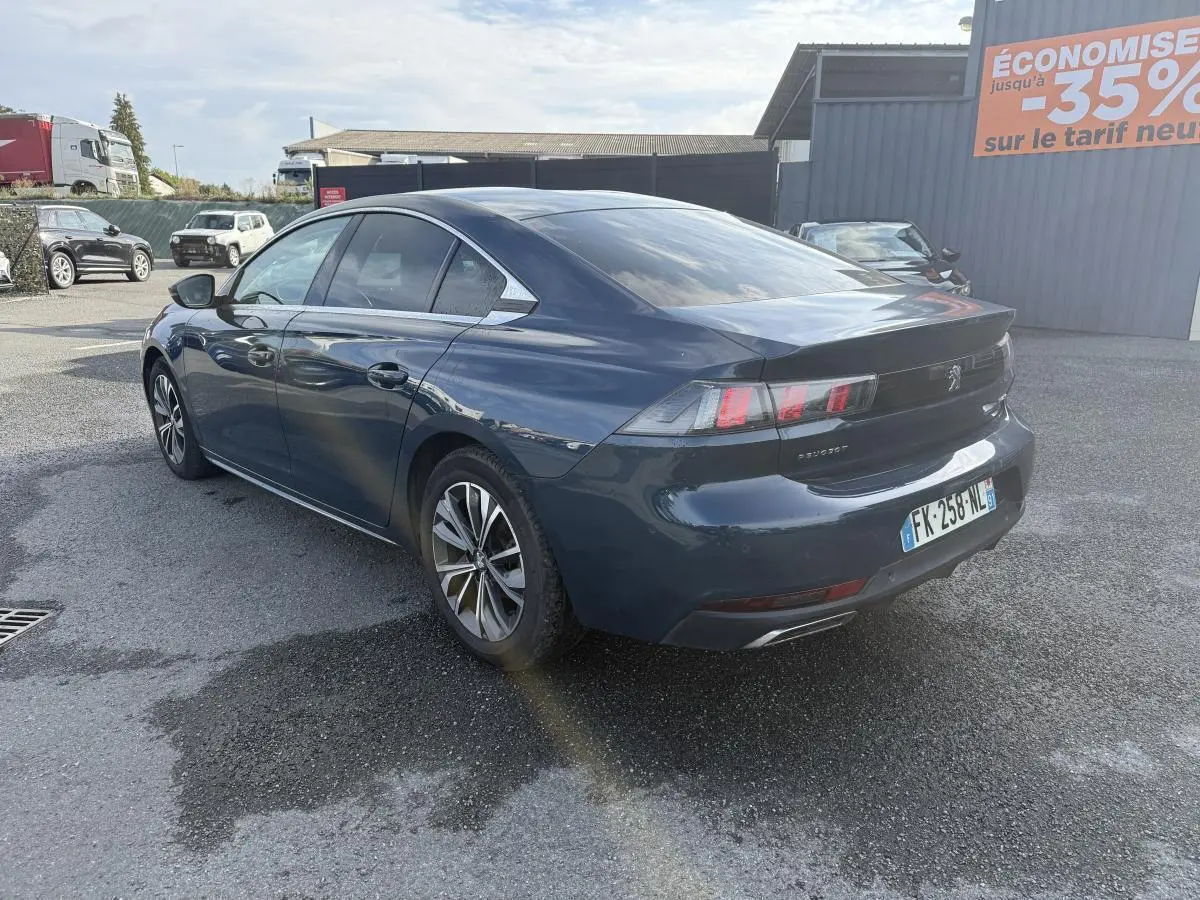 Peugeot 508 bleu métallisé vue 3/4 arrière droit, avec jantes alliage 17'' et feux arrière LED distinctifs.