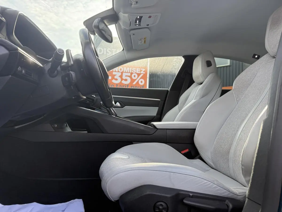 Vue latérale intérieure côté conducteur de la Peugeot 508 2019 avec sièges tissu gris clair et console centrale noire.