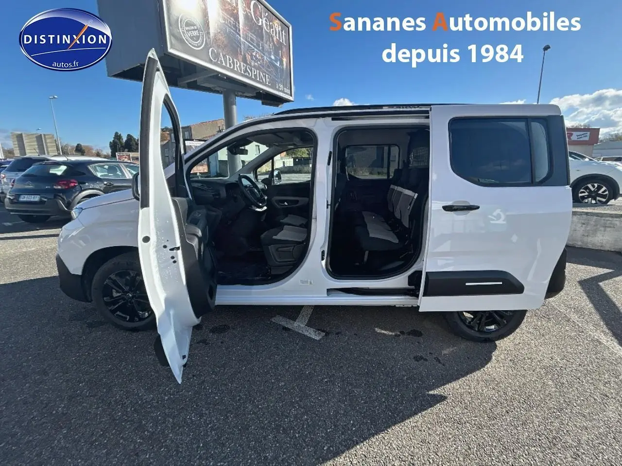 Vue latérale gauche d’un Citroën Berlingo blanc avec portes avant et latérale ouvertes, jantes noires et sièges arrière visibles.