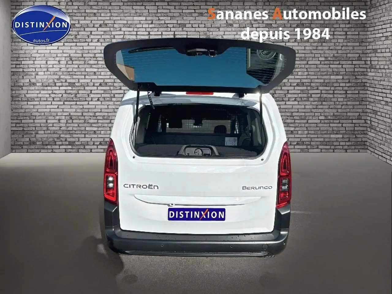 Vue arrière d'un Citroën Berlingo blanc avec hayon ouvert, feux rouges verticaux et pare-chocs noir.