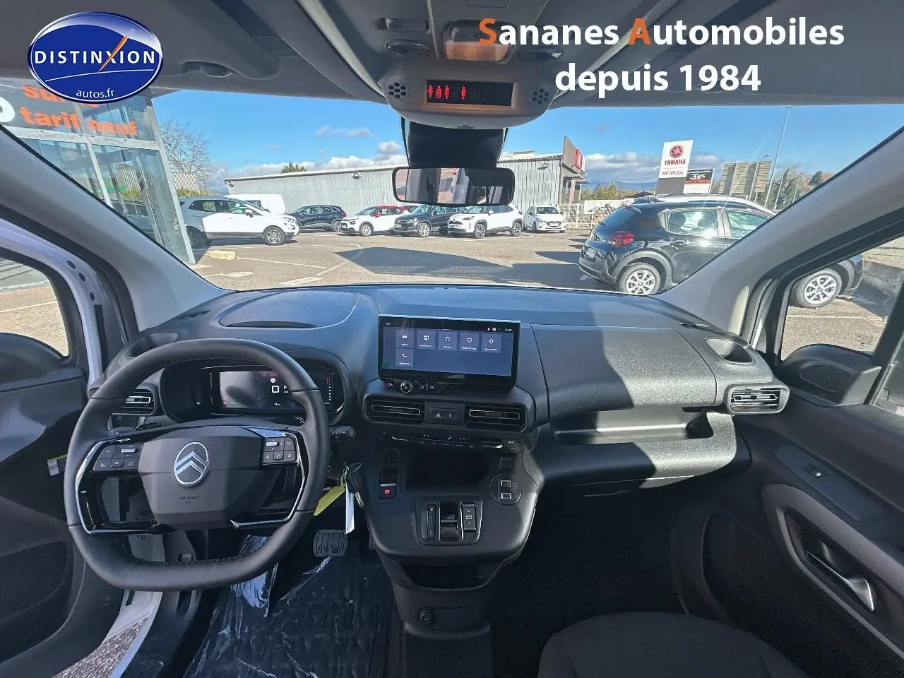 Vue intérieure avant du Citroën Berlingo blanc 2025, tableau de bord moderne avec écran tactile central et volant multifonction.