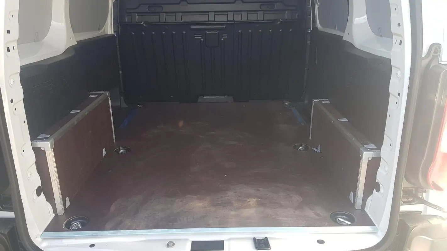Vue intérieure arrière du Citroën Berlingo blanc 2025, montrant l'espace de chargement vide avec plancher en bois.