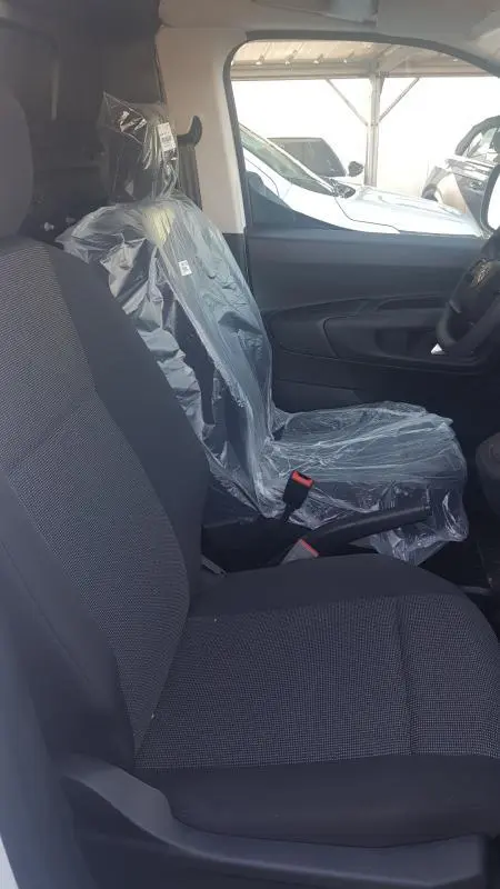 Vue intérieure côté droit du siège avant passager du Citroën Berlingo blanc 2025, siège protégé par housse plastique.